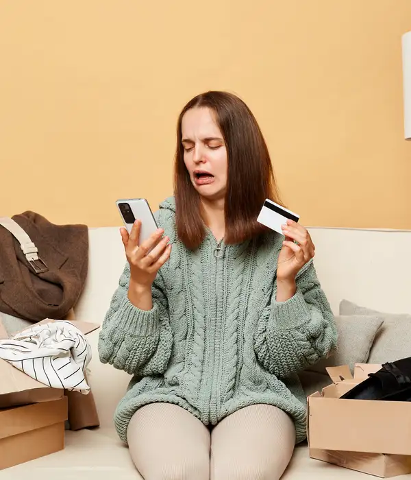 lost angels shopping addiction woman sitting couch holding credit card
