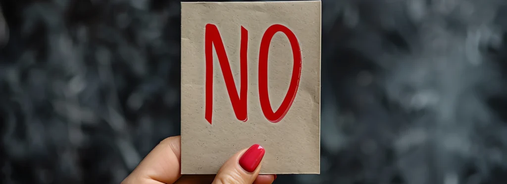 Hand holding a card with the word “NO,” symbolizing refusal to drink alcohol or resisting alcohol use